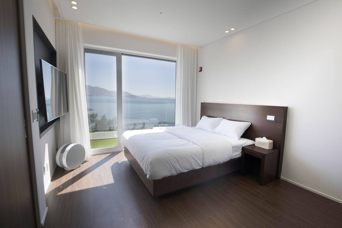 Ein modernes Hotelzimmer mit einem großen Bett, einem Fernseher und Meerblick.