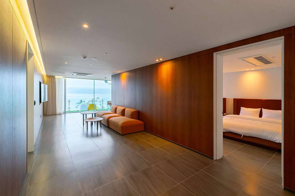 Ein modernes Hotelzimmer mit einem großen Bett, einer Sitzecke, einem kleinen Tisch und Blick auf die Stadt.