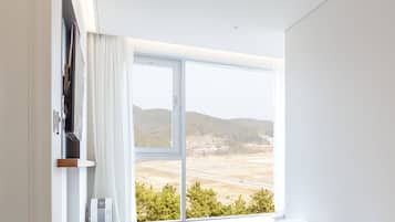 Una habitación con un gran ventanal que ofrece vistas a un paisaje con colinas y una carretera.