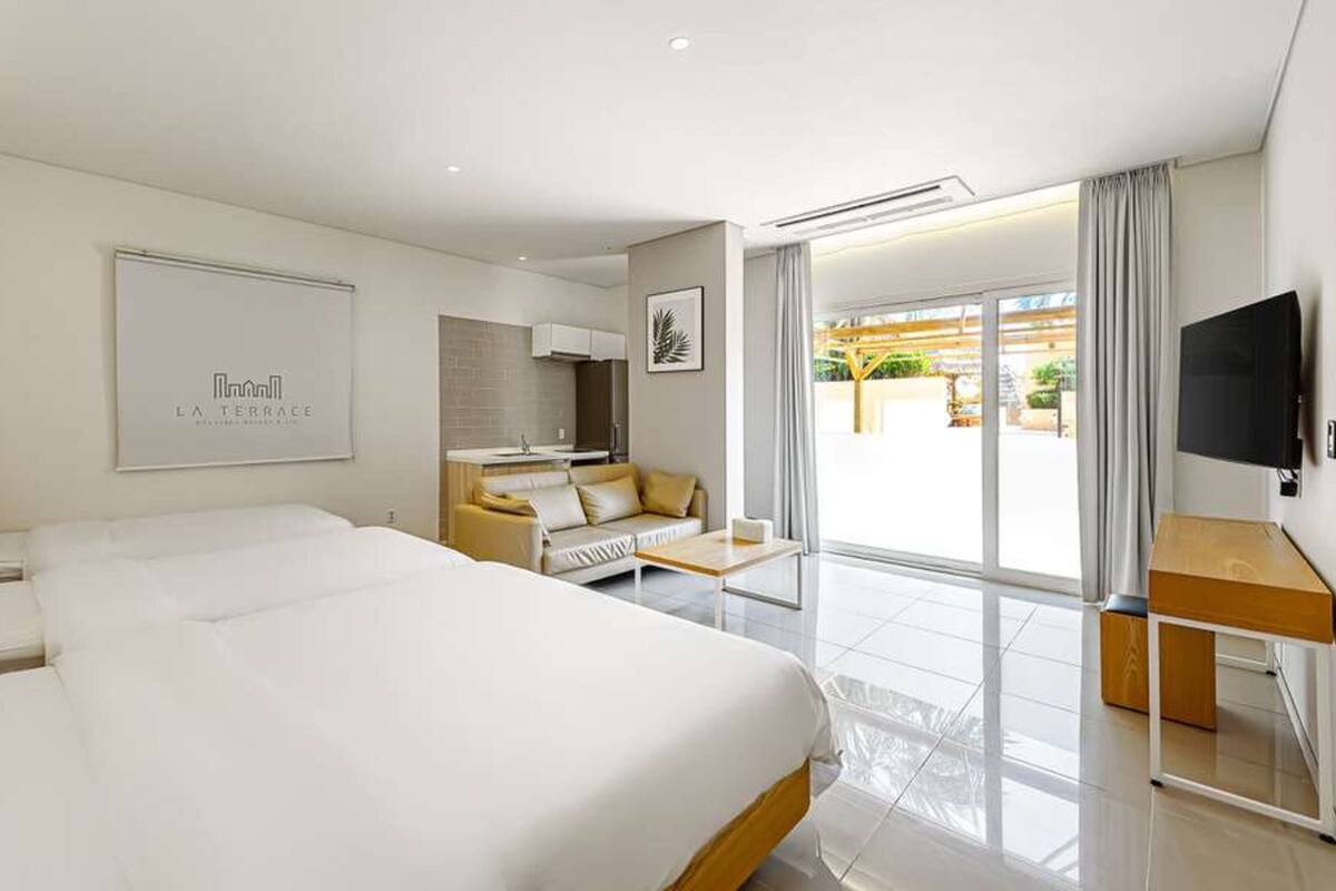 Ein Hotelzimmer mit einem großen Bett, einer Sitzecke, einem Fernseher und einem Balkon mit Blick.
