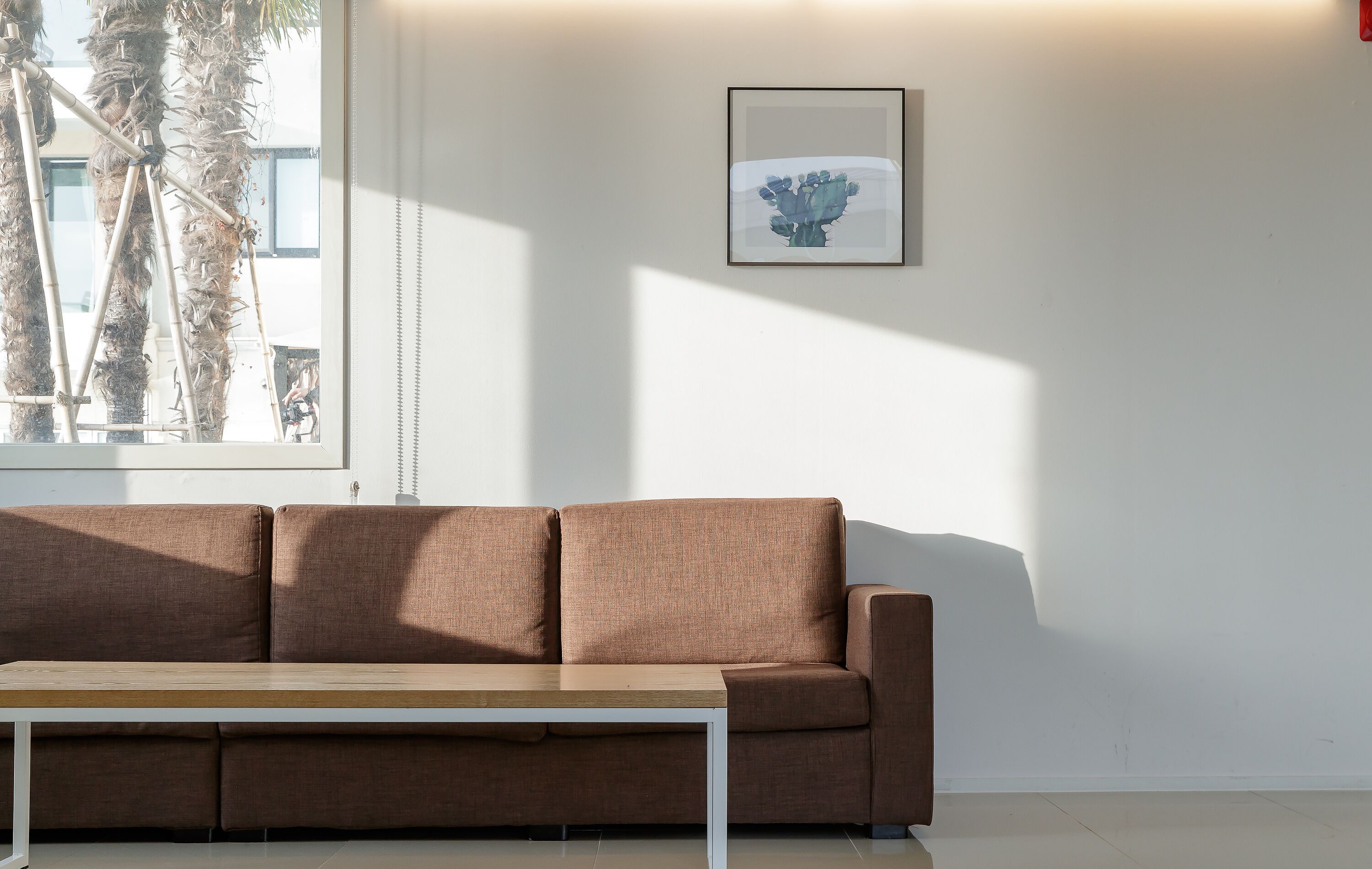 Ein modernes Wohnzimmer mit einem braunen Sofa, einem Holztisch und einem gerahmten Kunstwerk an der Wand.