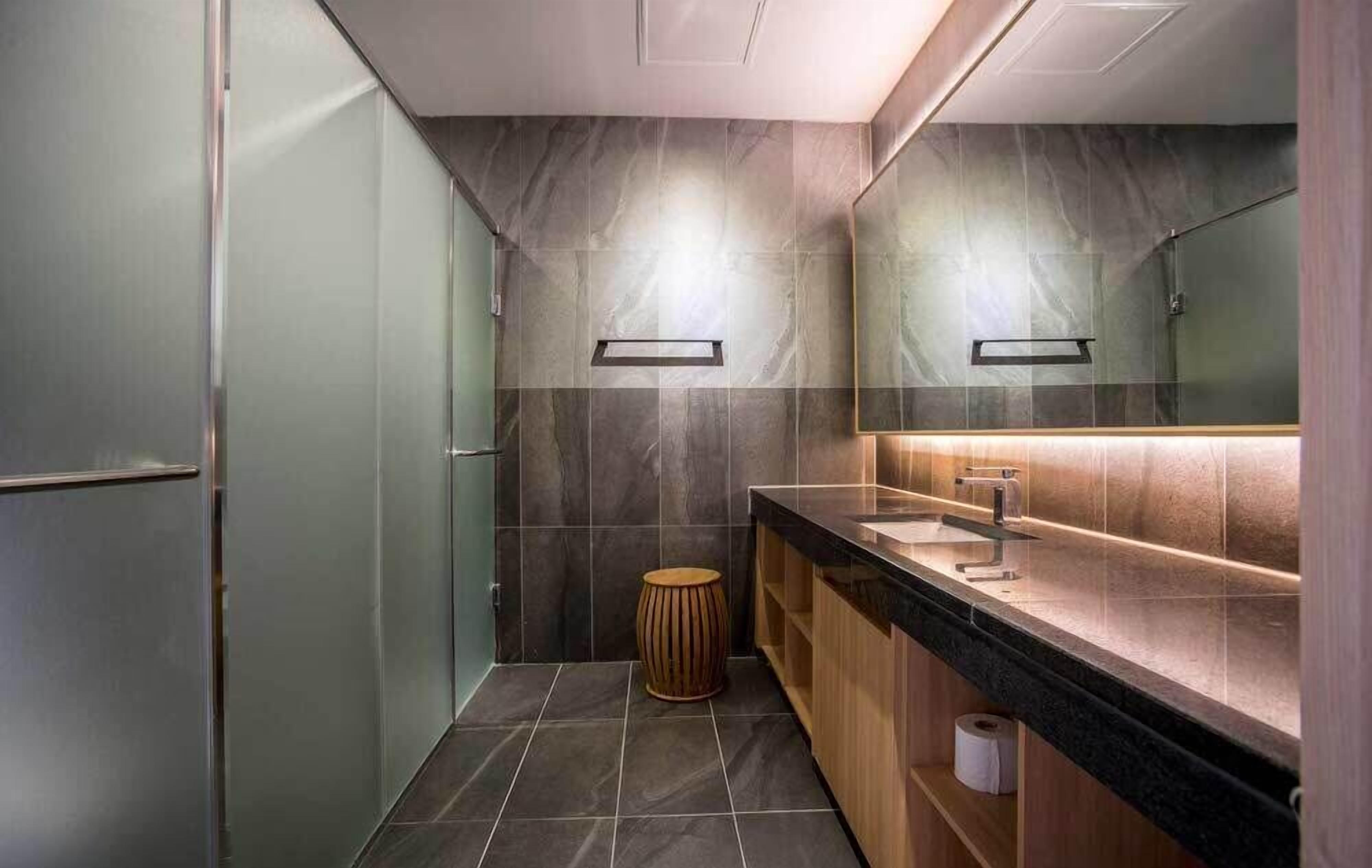 A modern bathroom with a large mirror, a sink, and a toilet.