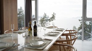 A dining table set for four with wine glasses, plates, and cutlery, overlooking a scenic view. - La Terrace Resort (Yeosu)