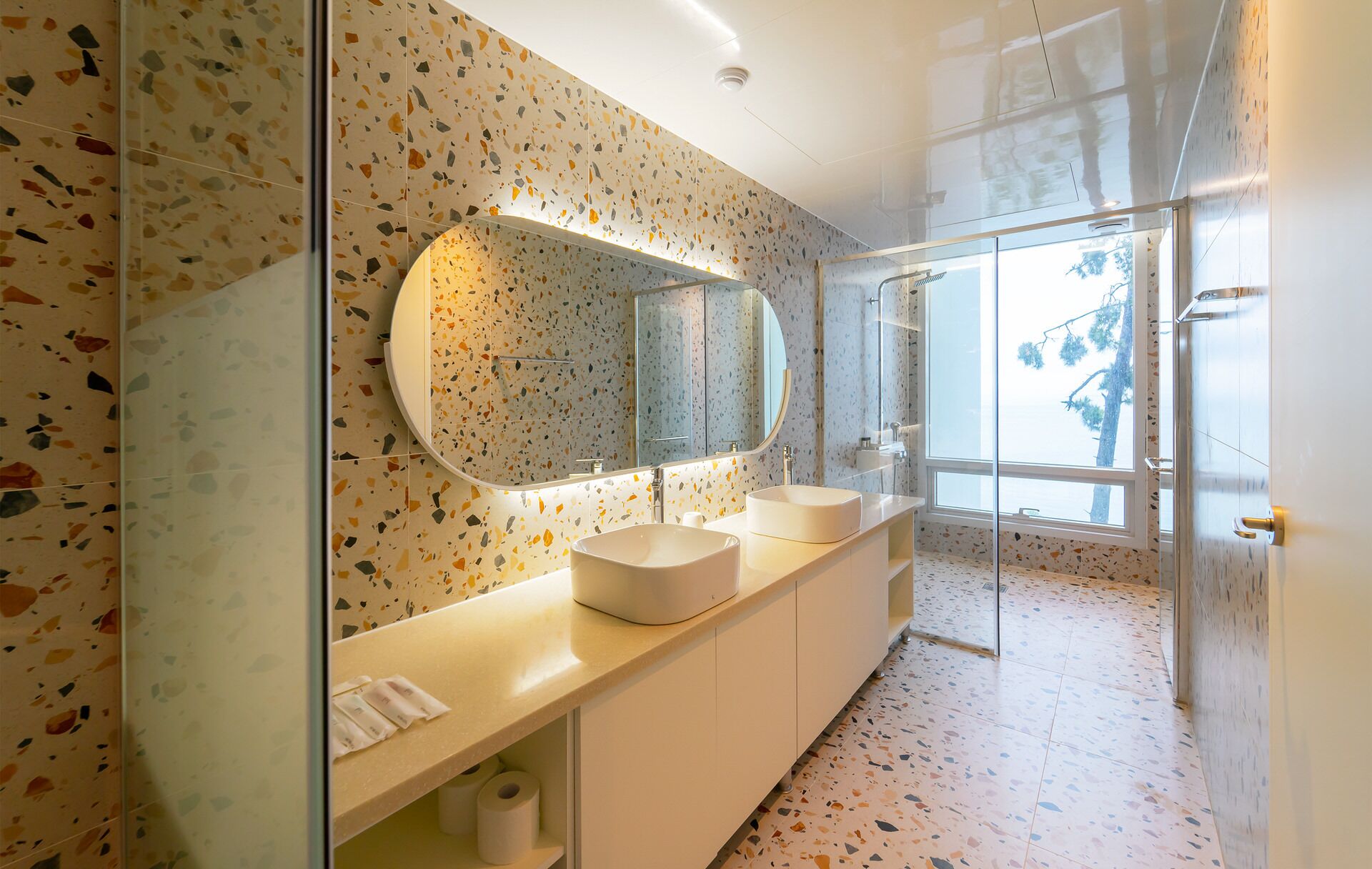 Un baño moderno con un espejo grande, dos lavamanos y una zona de ducha.