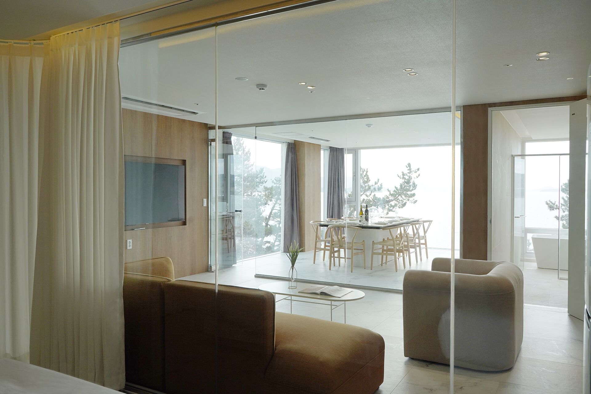 A modern living room with a sofa, armchair, and a dining area with a table and chairs.