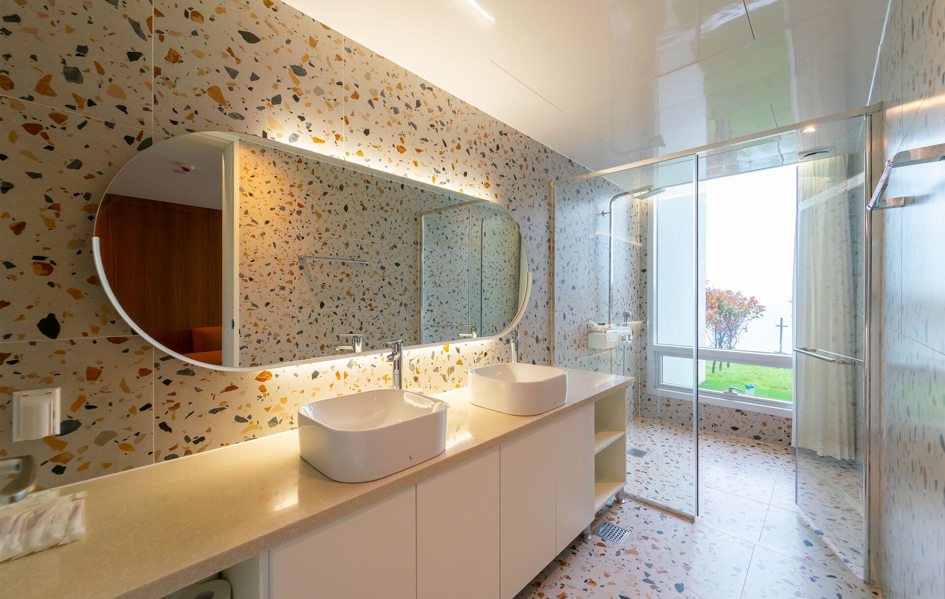 A modern bathroom with two sinks, a large mirror, and a shower area with a glass door.