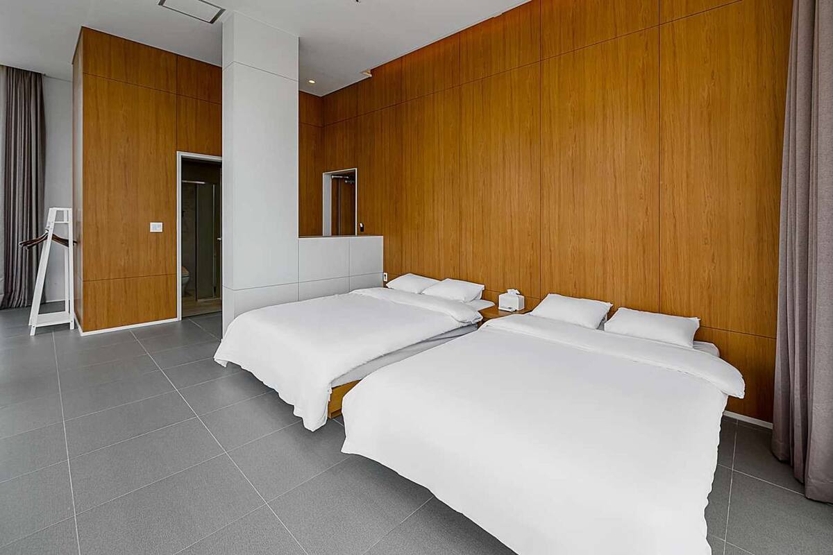 Ein modernes Hotelzimmer mit zwei Betten, einem großen Spiegel und einer Wand mit Holzelementen.