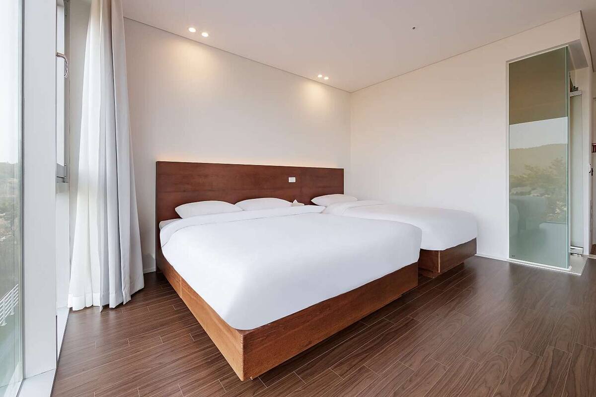Ein modernes Hotelzimmer mit einem großen Bett, einer Glastür und Blick auf die Stadt.