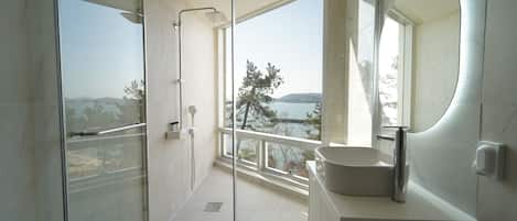 A modern bathroom with a glass-enclosed shower, a large sink, and a view of the outdoors.