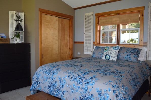 A bedroom with a large bed, wooden wardrobe, and a window with shutters.