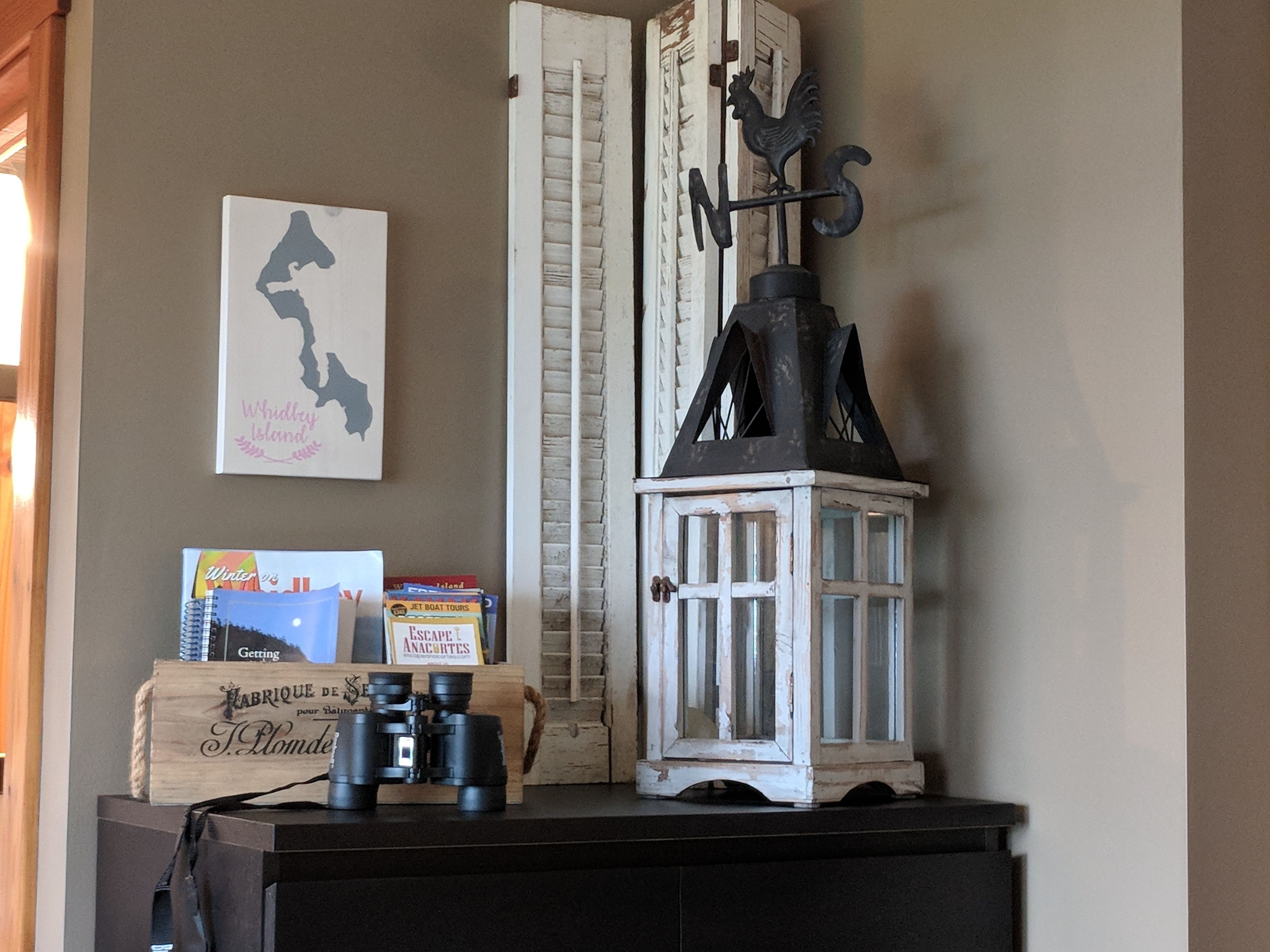 A wooden dresser with a white lantern, a framed map, and books.