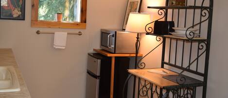 Eine kleine Küche mit Mikrowelle, Kühlschrank und einem Tisch mit Lampe.