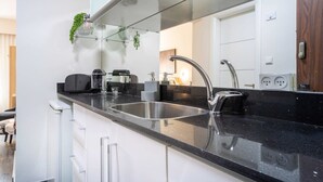 A modern kitchen with a black countertop, stainless steel sink, and white cabinetry. - Studio between King David Hotel and Waldorf - Parking Included (Jerusalem)