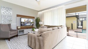 A modern living room with a beige sofa, a TV, and a ceiling fan.