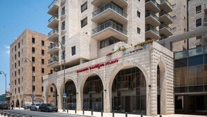 A multi-story building with a stone facade, large arched windows, and balconies. - Haneviim Court: 1BR Apartment in Jerusalem (Jerusalem)