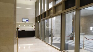 A reception area with a reception desk, a digital screen, and a glass partition. - Haneviim Court: 1BR Apartment in Jerusalem (Jerusalem)