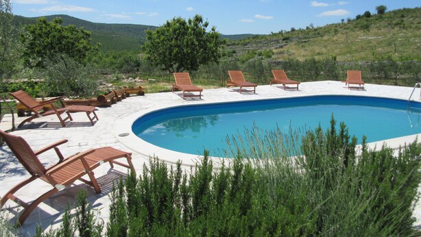 Ein Pool mit Liegestühlen und einer Stein-Terrasse.