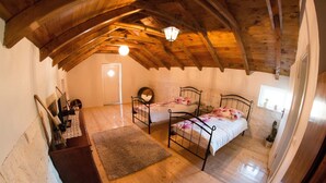 Ein Schlafzimmer mit zwei Betten, Holzboden, Holzbalkendecke, einem kleinen Teppich und einer Kommode.
