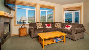 A cozy living room with a sectional sofa, a wooden coffee table, and a fireplace. - Ski-in Ski-Out Great Views Extra Large Living Room Top Floor Two Balconies (Mammoth Lakes)