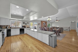 Una cocina amplia con una isla grande, armarios blancos y un comedor con mesa y sillas de madera.