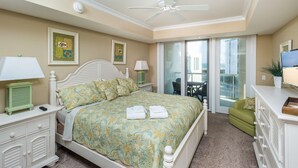 Un dormitorio con cama, mesita de noche, cómoda, ventilador de techo y vistas al exterior.