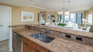 Una cocina con encimeras de granito, pileta de acero inoxidable y muebles de madera.