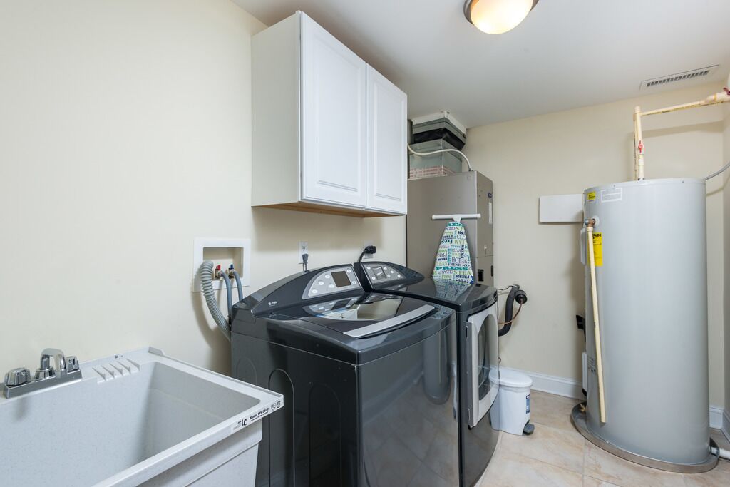 A compact laundry room with a washing machine, dryer, and a water heater.