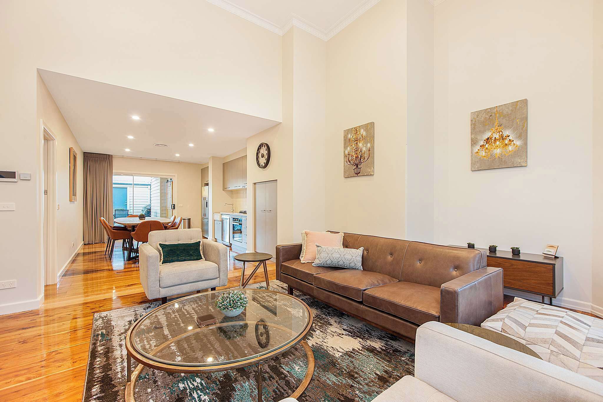 A modern living room with a sofa, armchairs, a coffee table, and a dining area with a table and chairs.