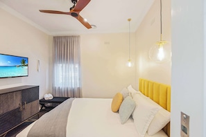Une chambre d’hôtel moderne équipée d’un lit, d’une télévision, d’un ventilateur de plafond et offrant une vue sur l’océan.