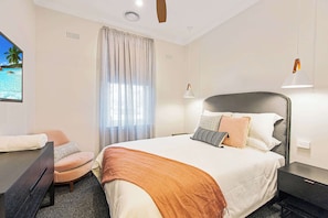Een hotelkamer met een bed, bureau, stoel en raam met gordijnen.