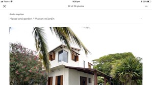 Une maison moderne avec une façade blanche, des volets en bois et un porche abrité.