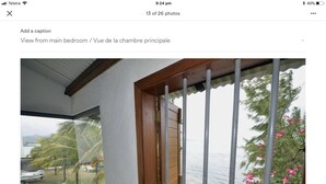 Une pièce dotée d’une grande fenêtre, d’une porte en bois et offrant une vue sur un jardin et un plan d’eau.