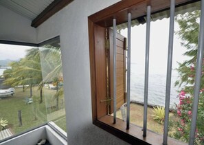 A room with a large window overlooking a garden and a body of water.