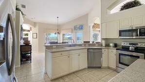 A spacious kitchen with a large island, stainless steel appliances, and a view of the outdoors. - Casa Del Sol, full refund*, heated pool, sleeps 6 (Port Charlotte)