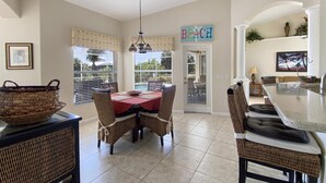 A dining area with a table and chairs, a basket on a table, and a sign that reads "BEACH". - Casa Del Sol, full refund*, heated pool, sleeps 6 (Port Charlotte)
