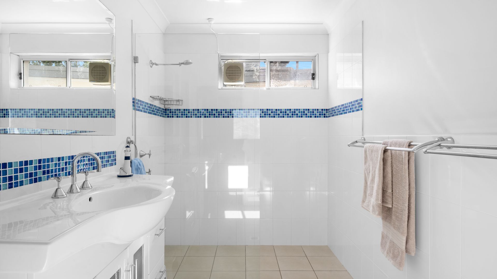 A modern bathroom with a white sink, mirror, and shower.