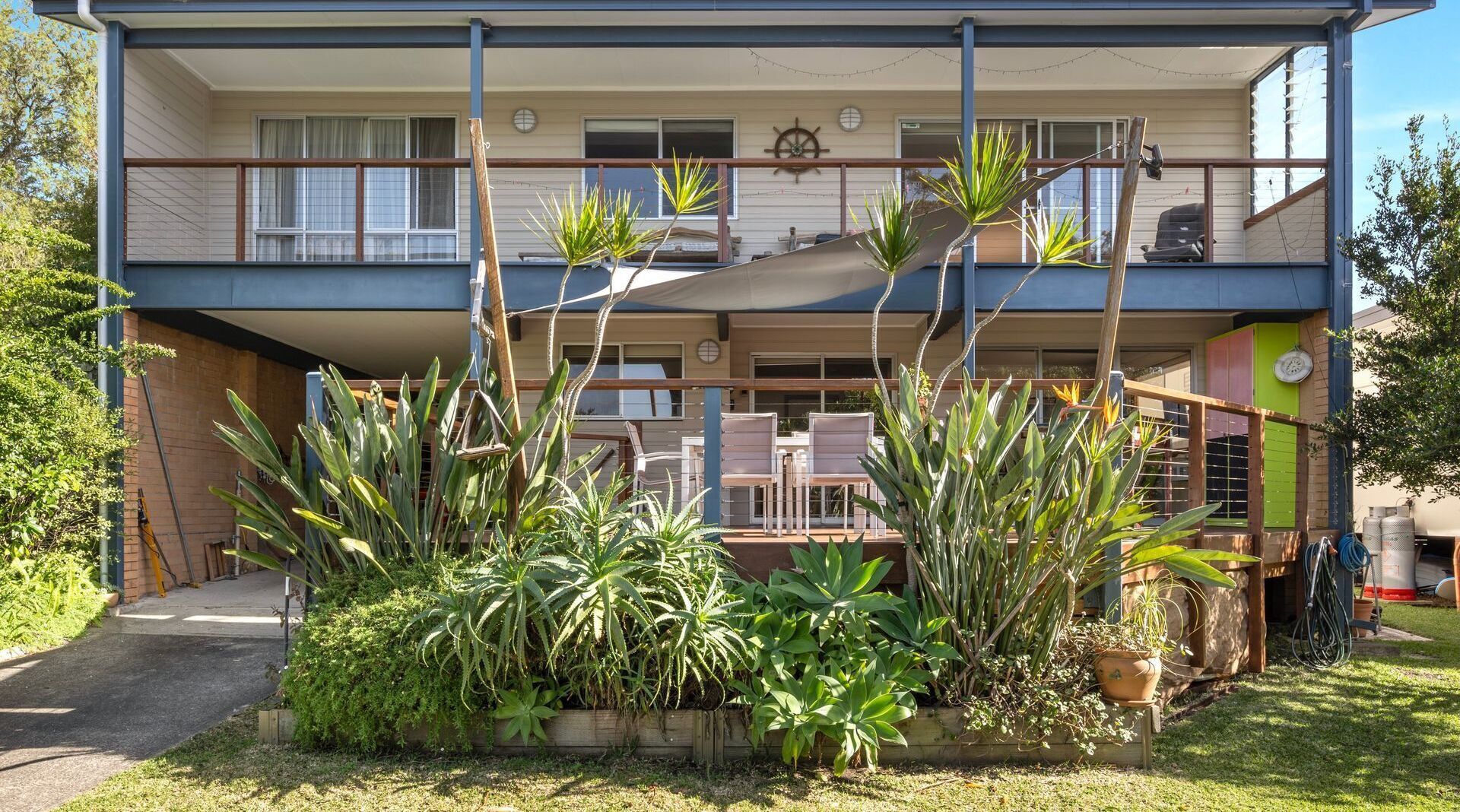 A two-story building with a balcony, outdoor seating area, and various potted plants.