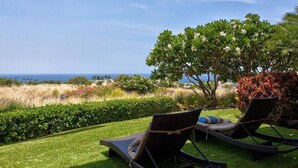 Two lounge chairs with cushions on a well-manicured lawn, overlooking a coastal landscape with a clear view of the sea. - Wai'ula'ula: You Can't Beat This View  (Waimea)