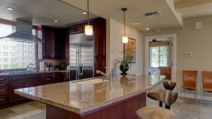 A modern kitchen with a large island, stainless steel appliances, and a view to the dining area. - Wai'ula'ula: You Can't Beat This View  (Waimea)
