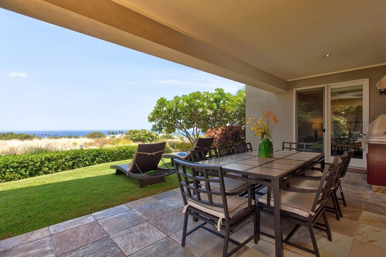 An outdoor patio with a dining table, chairs, and a grill.