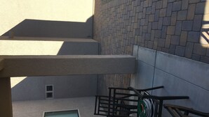 Eine Gebäudeecke mit Backsteinmauer, Fenster und Metallgeländer.