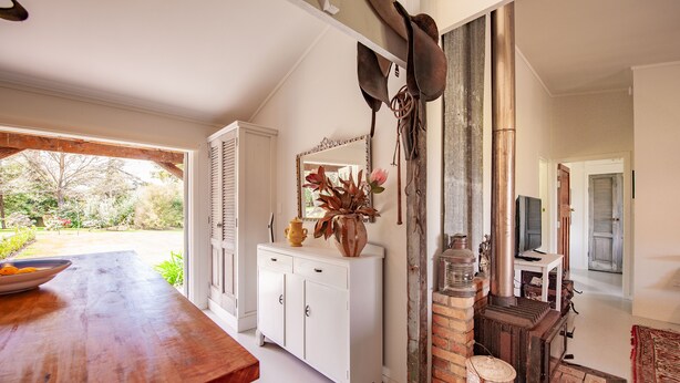 A dining area with a wooden table, white cabinetry, and a brick fireplace. - Stables Cottage; awaken to the sound of a river flowing over rapids. <br><br> (Frasertown)