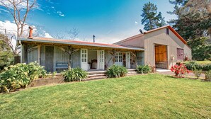 A two-story house with a porch, a garage, and a well-maintained lawn. - Stables Cottage; awaken to the sound of a river flowing over rapids. <br><br> (Frasertown)