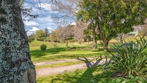 A grassy landscape with trees and a path. - Stables Cottage; awaken to the sound of a river flowing over rapids. <br><br> (Frasertown)