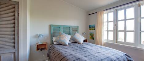 A bedroom with a bed, a nightstand, a lamp, and a window with curtains.