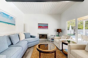 A modern living room with a sectional sofa, a fireplace, and a view of the outdoors.