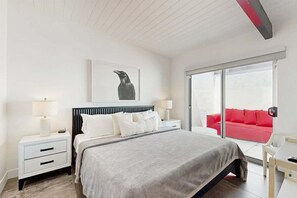 A hotel room with a bed, bedside tables, a red sofa, and a large window. - Happy Hour - Iconic Mid Mod Palm Springs (Palm Springs)