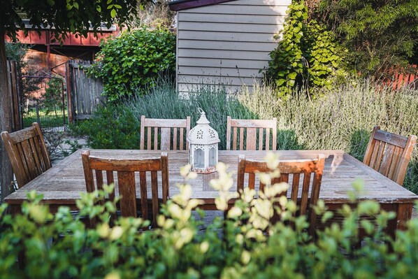 Enjoy al fresco dining in a serene garden setting, surrounded by lush greenery and a charming lantern.