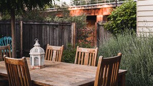 A wooden table with four chairs and a white lantern in a rustic outdoor setting. - The Station Master's House, A darling house with everything you need for a relaxing getaway in Castl... (Castlemaine)