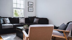 A modern living room with a black sofa, a wooden coffee table, and a grey armchair. - The Station Master's House, A darling house with everything you need for a relaxing getaway in Castl... (Castlemaine)